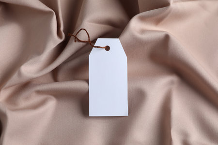 Blank tag with string on beige fabric, top viewの写真素材