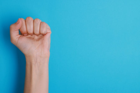 Woman with visible hand veins on light blue background, closeup. Space for textの写真素材