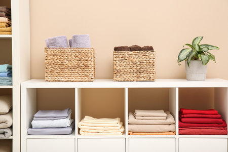 Folded linens and towels on shelving unit indoors. Home textile storageの写真素材