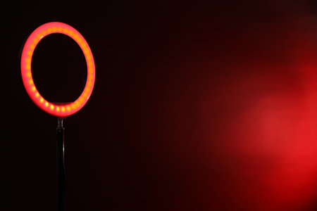 Ring lamp on stand against dark red background, space for textの写真素材