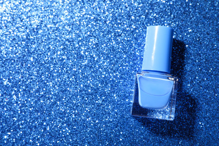 Nail polish in bottle on blue glitter surface, top view. Space for textの写真素材