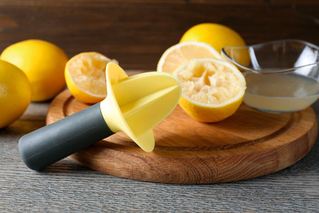 Plastic juicer and fresh lemons on grey wooden table, closeupの写真素材