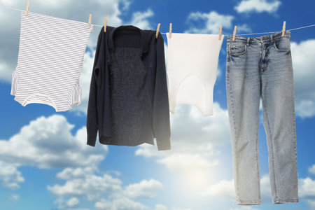 Different clothes drying on washing line against blue skyの写真素材