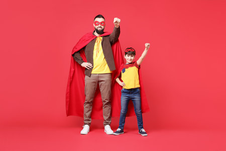 Father and his son wearing superhero costumes on red backgroundの写真素材