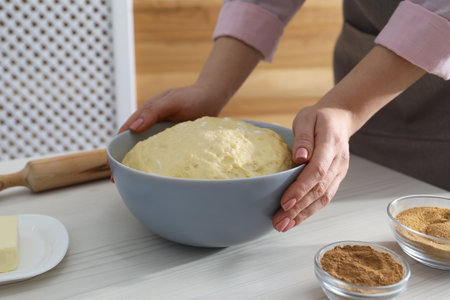 Making cinnamon rolls. Woman with dough at white wooden table, closeupの写真素材