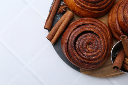 Cinnamon roll buns and spices on white tiled table, top viewの写真素材