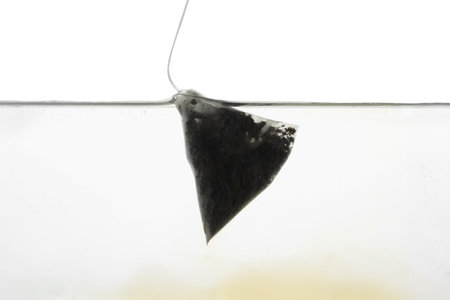 Putting tea bag into glass cup on white background, closeupの写真素材