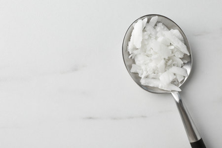 Soy wax in spoon on white marble table, top view. Space for textの写真素材