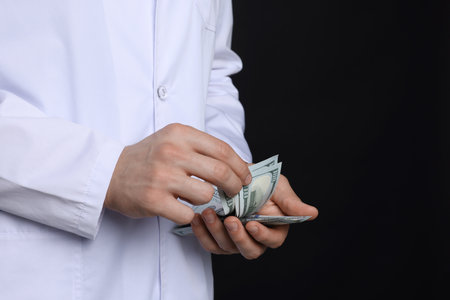 Doctor with dollar banknotes on black background, closeupの写真素材