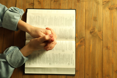 Woman with open Holy Bible praying at wooden table, top viewの写真素材