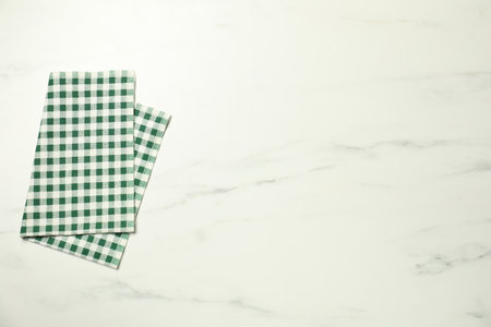 Green checkered napkin on white marble table, top view. Space for textの写真素材