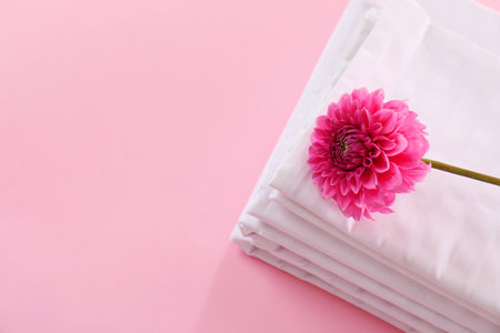 Stacked clean bed lines and flower on pink background, top view. Space for textの写真素材