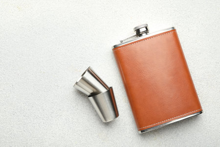 Hip flask and cups on light gray table, flat lay. Space for textの写真素材