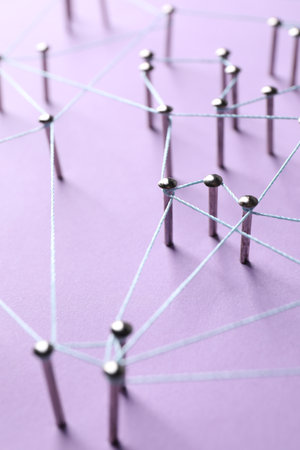 Network connection. Nails linked together by thread on violet background, closeupの写真素材