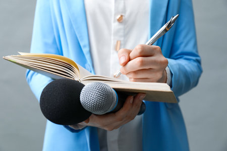 Journalist with microphones taking notes on gray background, closeupの写真素材