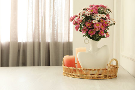 Stylish vase with beautiful flowers and candles on white wooden table at home, space for textの写真素材