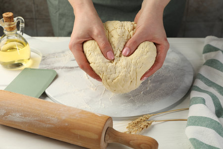 Woman kneading dough at white wooden table, closeupの写真素材