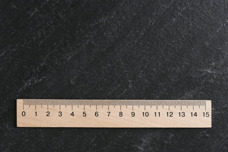 One wooden ruler on black table, top view. Space for textの写真素材