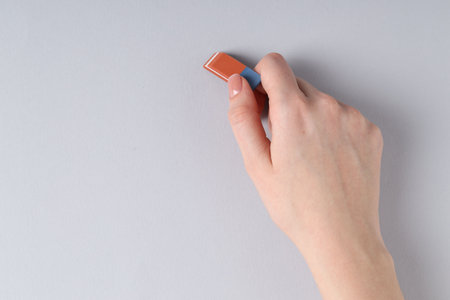 Woman using eraser on gray background, closeup. Space for textの写真素材