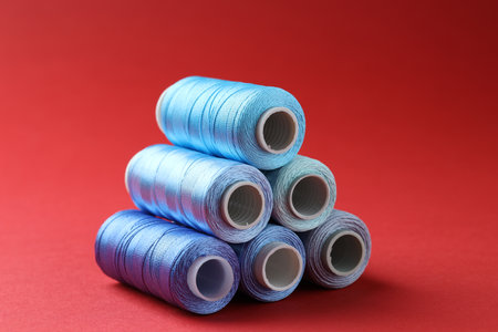 Spools of colorful sewing threads on red background
