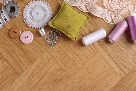 Sewing threads and other supplies on wooden table, flat lay. Space for text