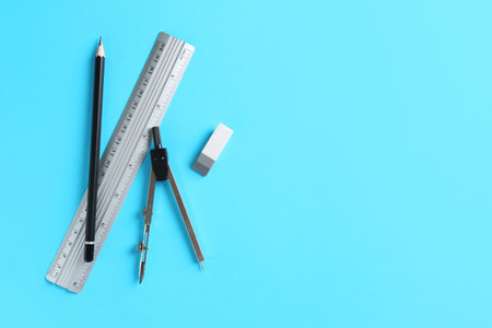 Ruler, pencil, eraser and compass on light blue background, flat lay. Space for text
