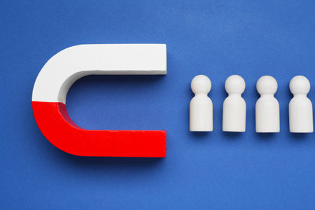 Magnet attracting human figures on blue background, flat layの写真素材