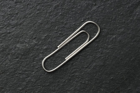 One metal paper clip on black table, top viewの写真素材