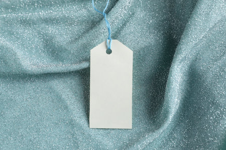 Blank tag with string on teal fabric, closeupの写真素材