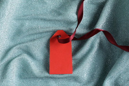 Blank tag with ribbon on teal fabric, top viewの写真素材