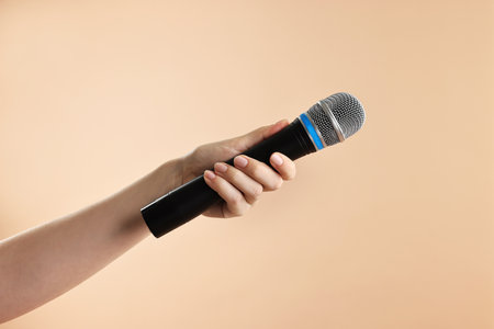 Woman with microphone on beige background, closeupの写真素材