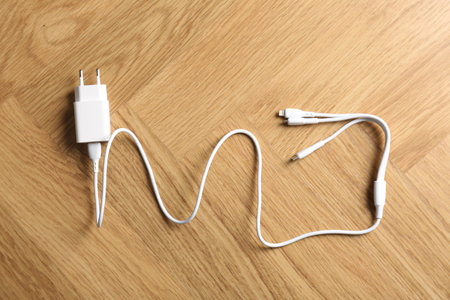 USB power adapter with triple charge cable on wooden table, top view