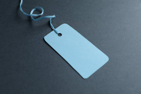 Blank tag with string on gray background, closeup