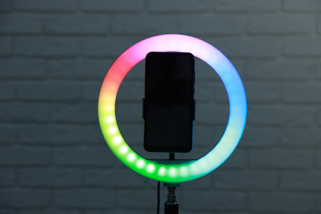 Ring lamp with smartphone against brick wall
