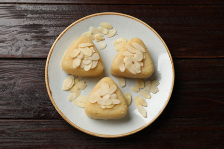 Pieces of delicious semolina halva with almond flakes on wooden table, top view