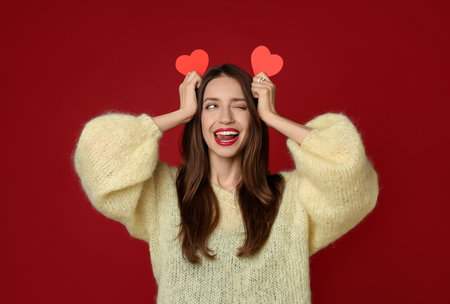 Happy Valentine's Day. Beautiful woman with paper hearts on red backgroundの写真素材