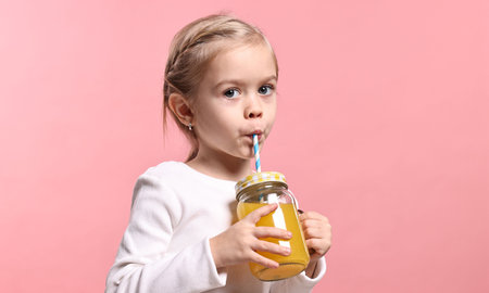 Girl with mason jar of orange juice on pink background. Refreshing drinkの写真素材