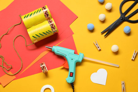 Hot glue gun and handicraft materials on orange background, flat layの写真素材