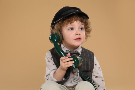 Cute little boy with telephone handset on beige backgroundの写真素材