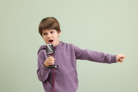 Cute boy with microphone singing near green wallの写真素材