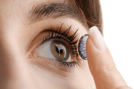 Woman putting in blue color contact lens on white background, closeupの写真素材