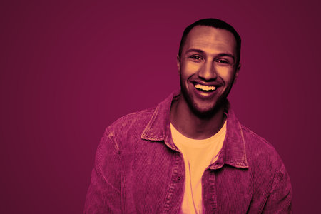 Handsome man smiling in neon light, space for text