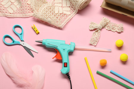 Hot glue gun and handicraft materials on pink background, flat layの写真素材