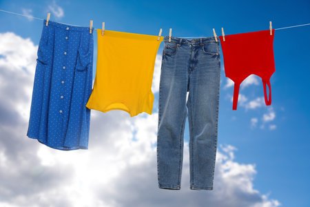 Different clothes drying on washing line against blue skyの写真素材