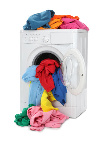 Modern washing machine with colorful laundry isolated on whiteの写真素材