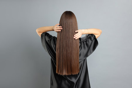 Teenage girl with healthy long hair on light grey background, back viewの写真素材