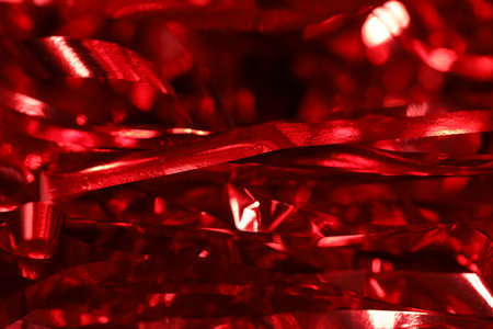 Shiny red tinsel as background, closeup view
