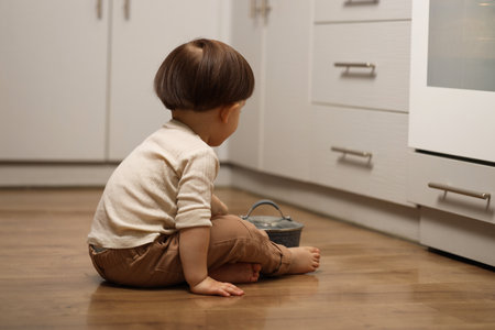 Little boy playing with pot in kitchen. Dangerous situationの写真素材