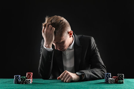 Sad young man with casino chips at gambling table. Poker conceptの写真素材