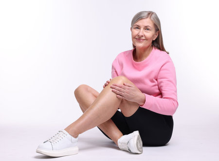 Senior woman suffering from knee pain on white backgroundの写真素材